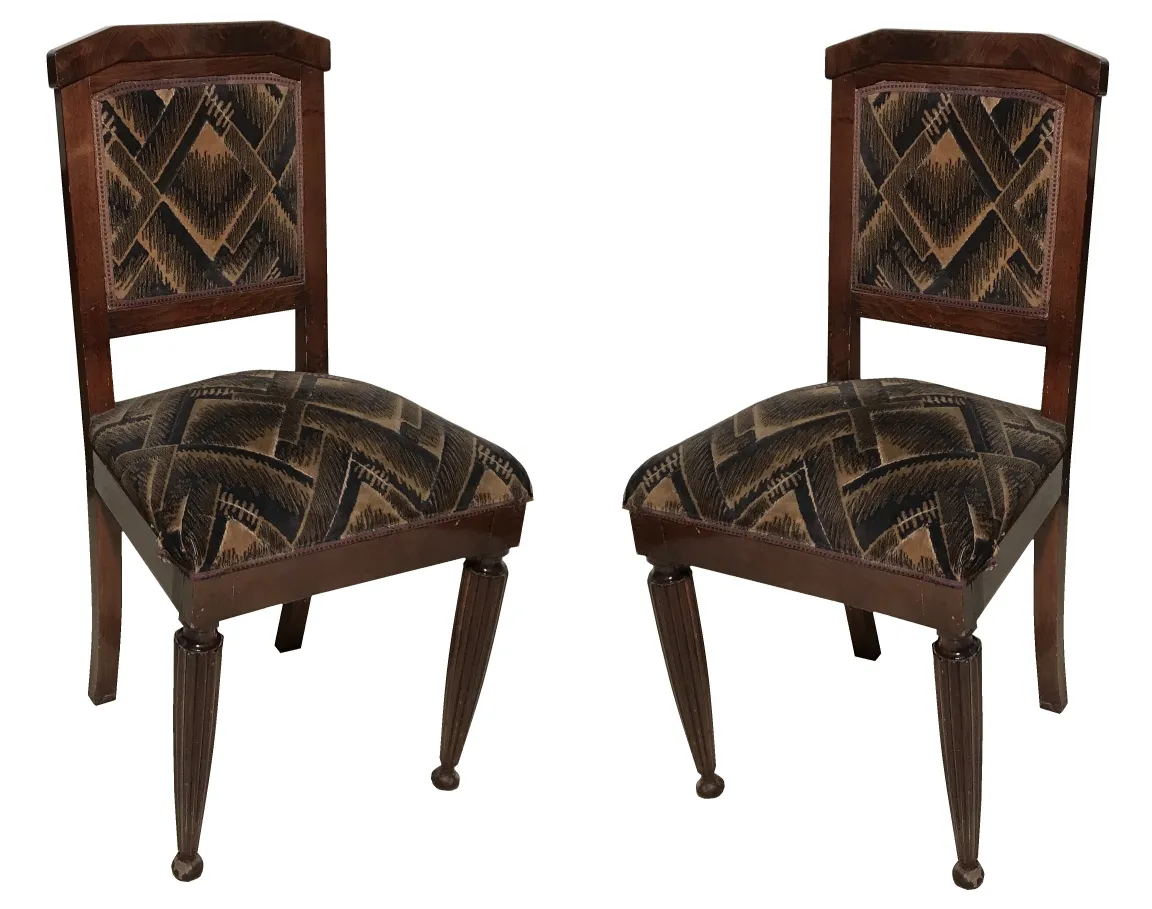 Deux chaises antiques, à restaurer, avec des sièges à motifs, dans un cadre accueillant.