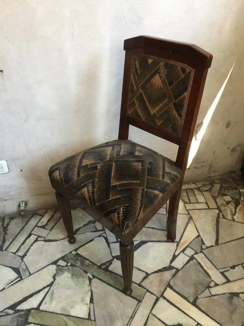 Duas cadeiras antigas com design geométrico em um ambiente rústico.