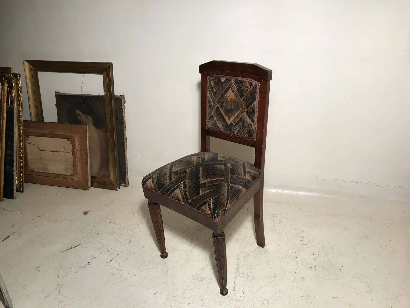 Deux chaises antiques avec un design distinctif dans un cadre vintage, l'une en cours de restauration.