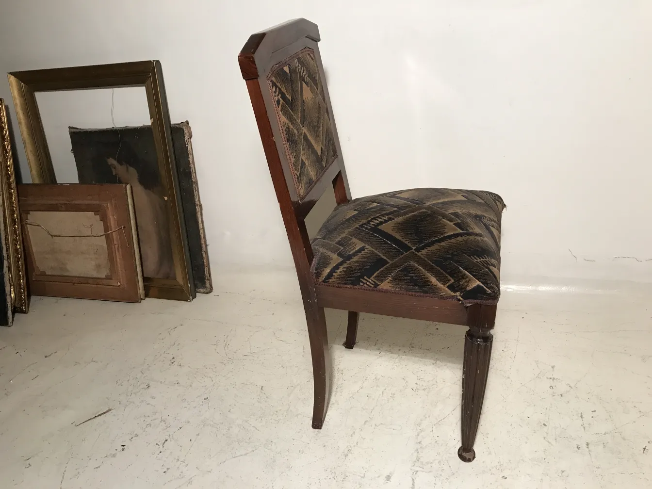 Deux chaises anciennes avec un design art deco, adaptées à la restauration. Arrière-plan avec des cadres.