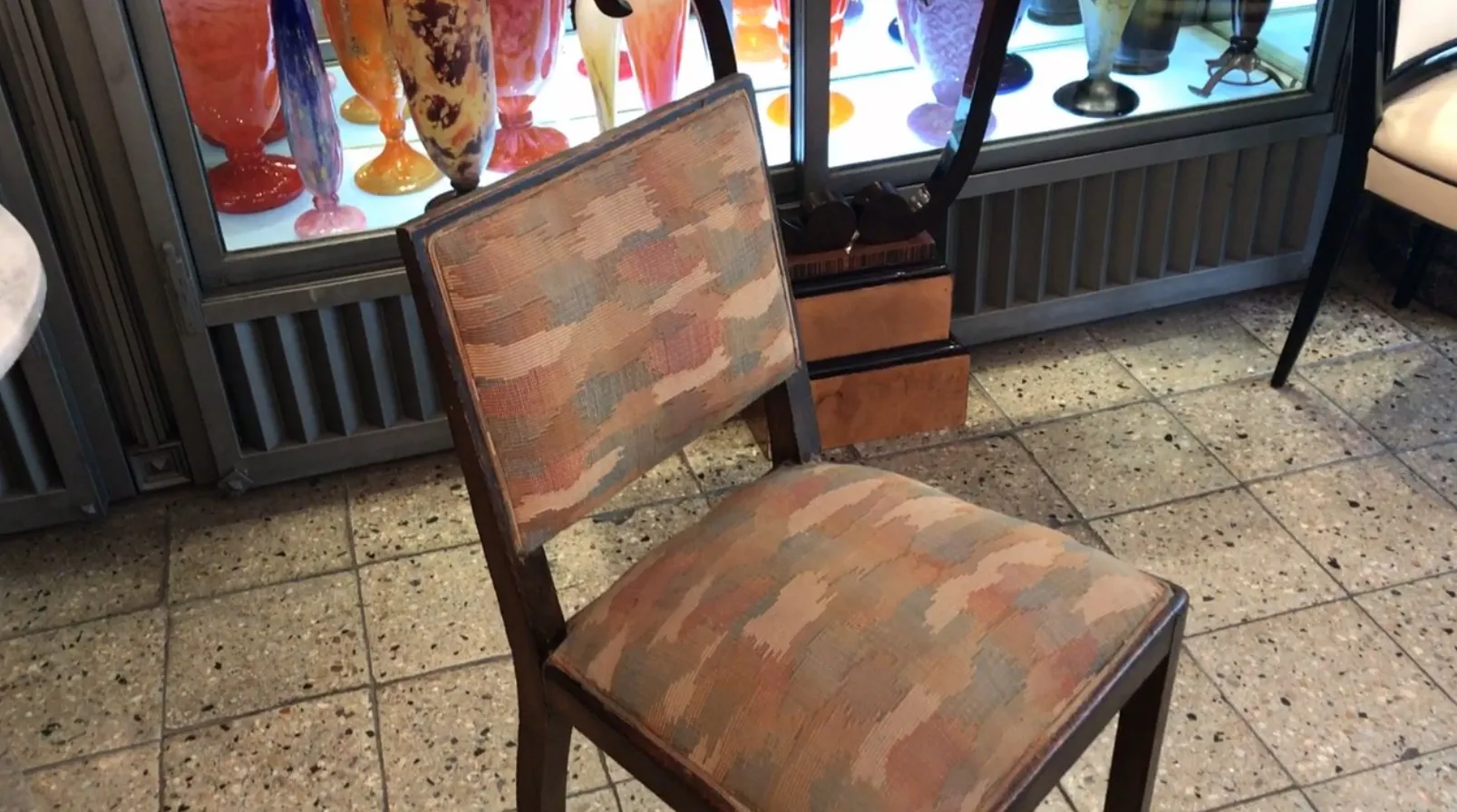 Chaise ancienne avec un rembourrage coloré, dans un environnement artistique décoratif.