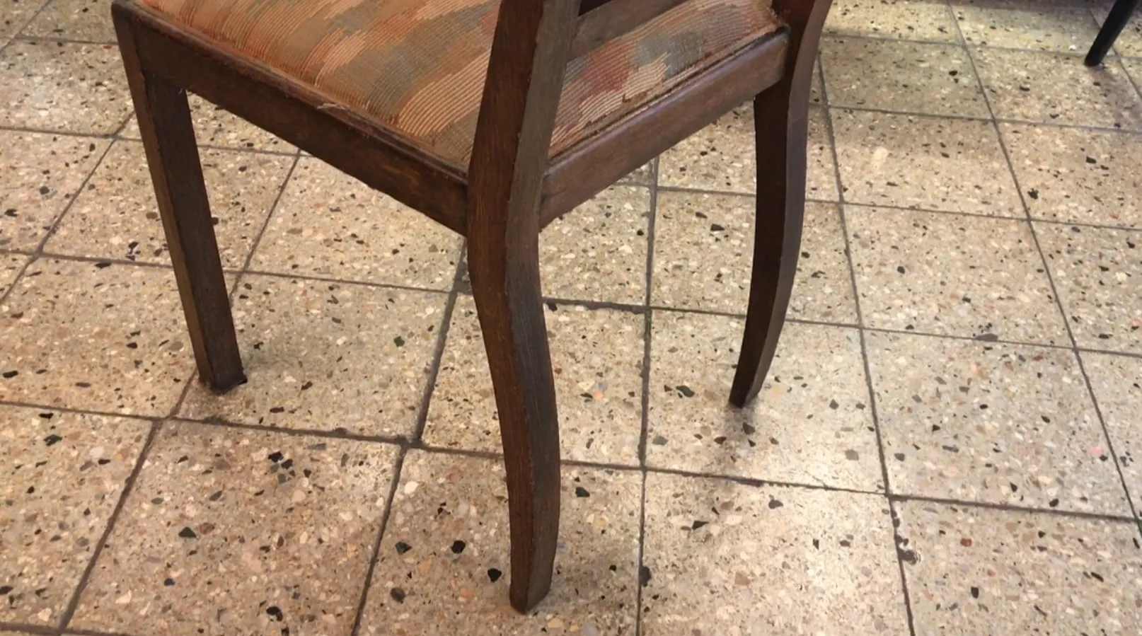 antique chair in a neutral setting, featuring a classic design. Stone floor.