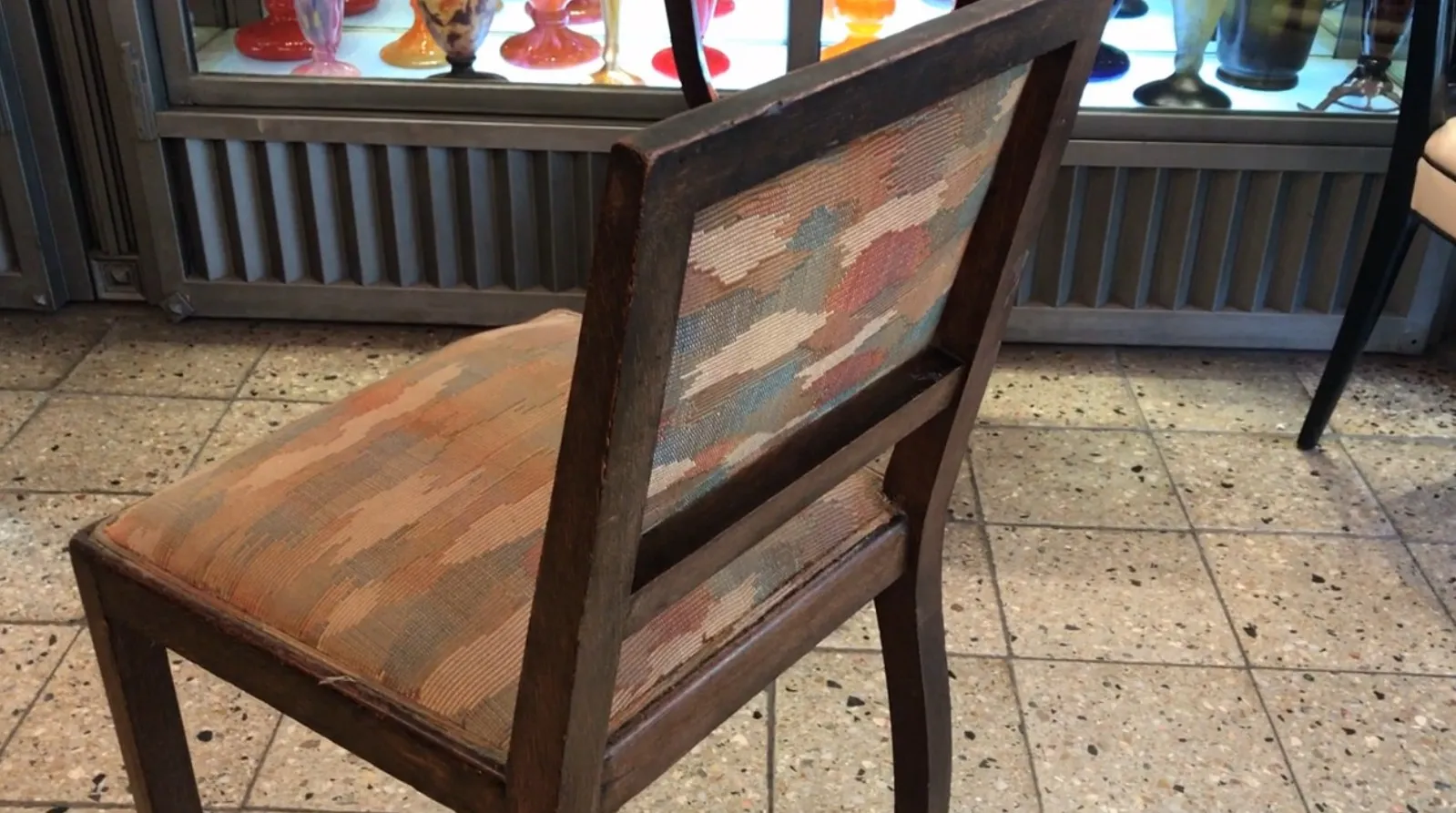 cadeira antiga com encosto decorado em ambiente de antiguidades