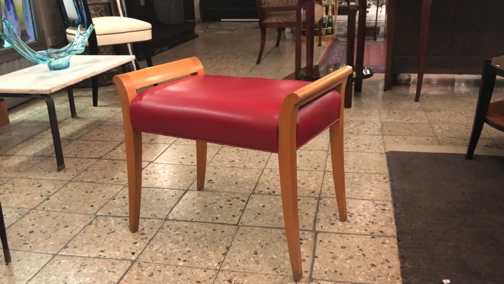 banqueta antiga vermelha com pernas claras em um ambiente elegante