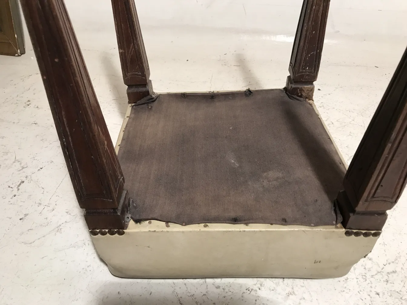Vue d'un tabouret ancien, pattes détaillées, surface simple.