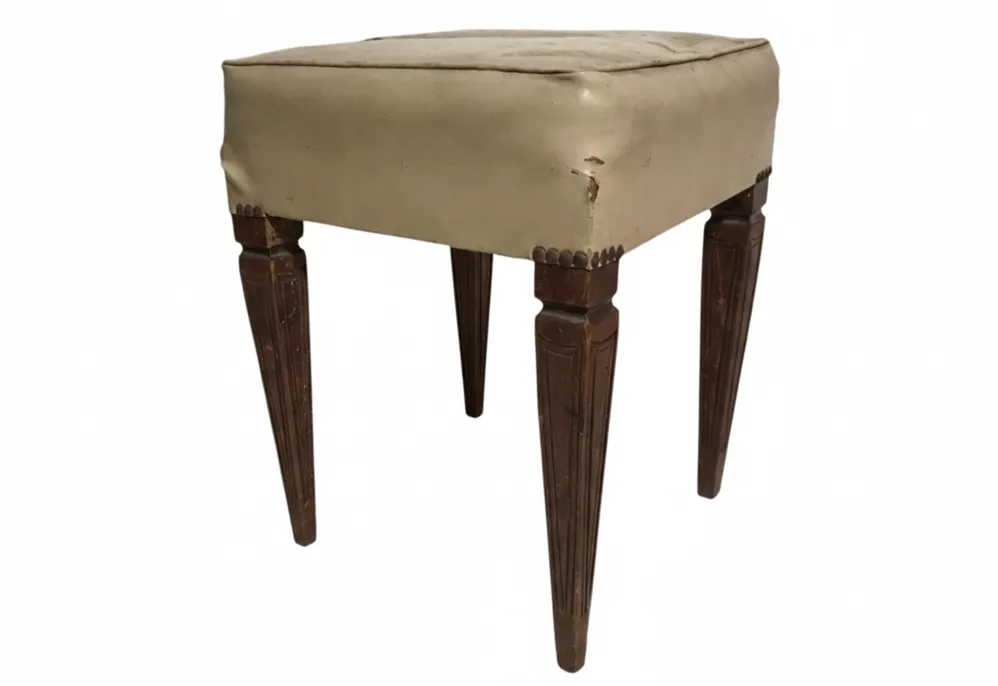 Antiker Hocker mit weicher Polsterung und dekorativen Beinen, Vintage-Ambiente.