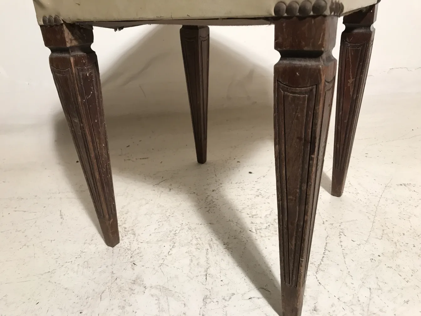 banqueta antigua con patas decoradas y tapizado claro, ideal para decoración