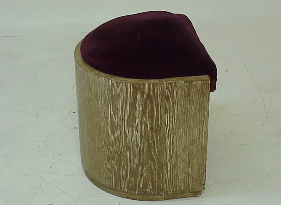 banqueta antigua con asiento acolchado en burdeos en un entorno neutro