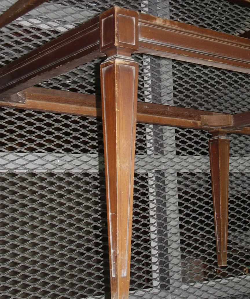 Ancienne tabouret avec pattes fines, arrière-plan industriel.