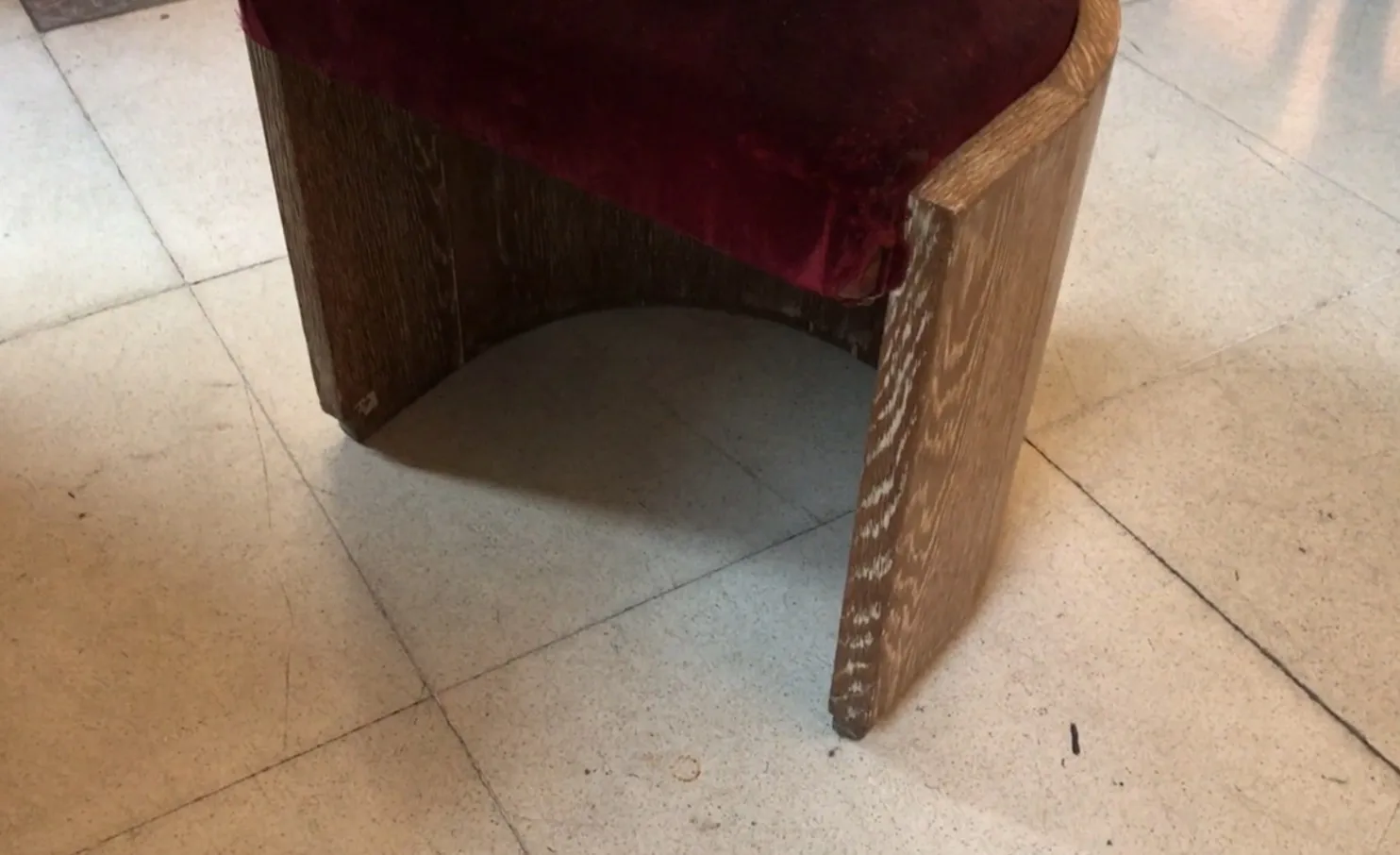 Antiker Hocker mit rotem Samtbezug und einfachem Design, gemütliche Atmosphäre.