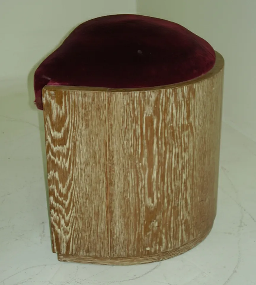 Antiker Hocker mit runder Form und burgunderfarbigem Bezug.