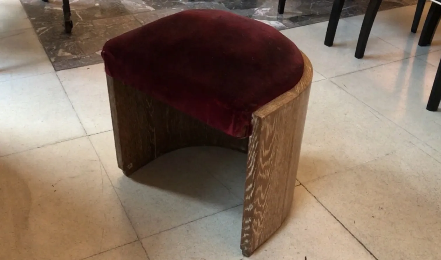 Antique stool with burgundy padded seat.