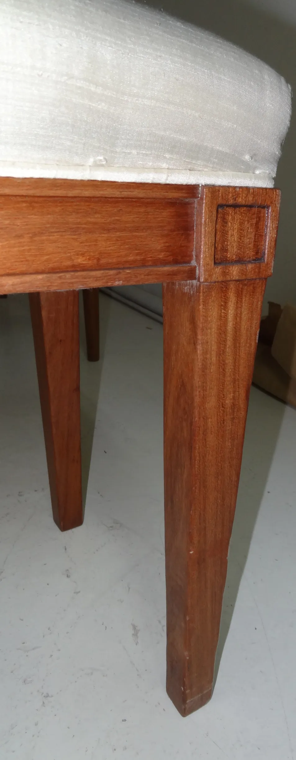 Side view of an antique sidewalk stool with straight legs and simple design.