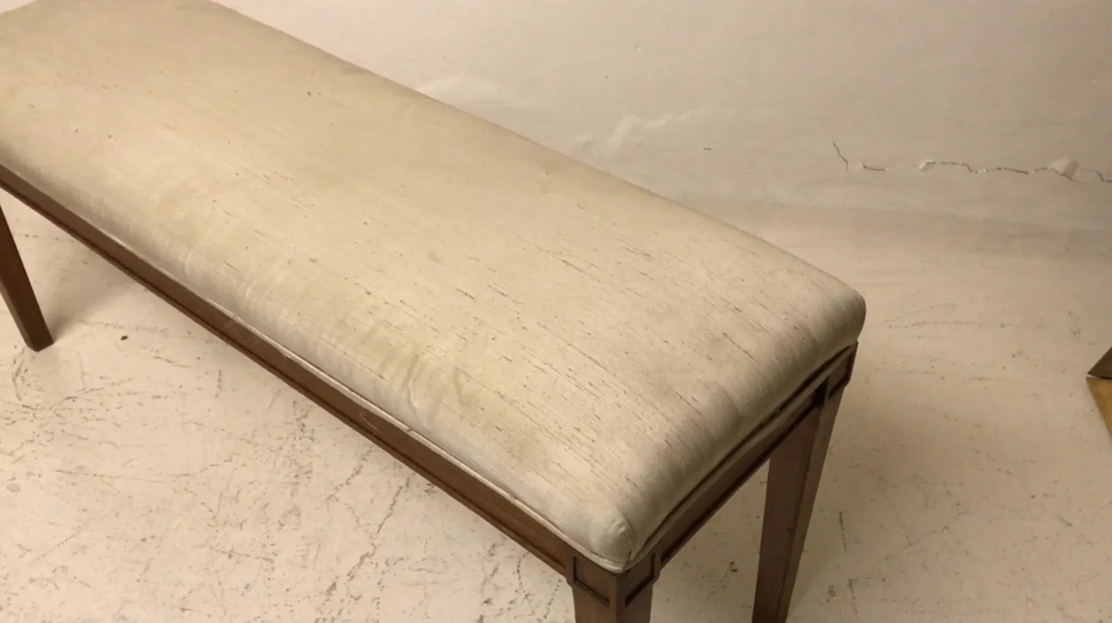 Ancien tabouret avec coussin clair dans un cadre minimaliste.