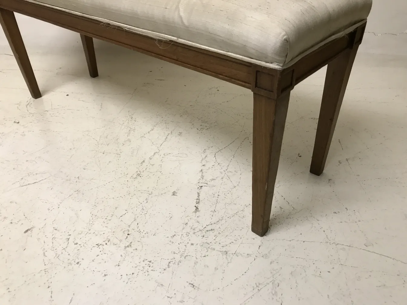 Antique bench with simple design and white seat, on a clean light background.