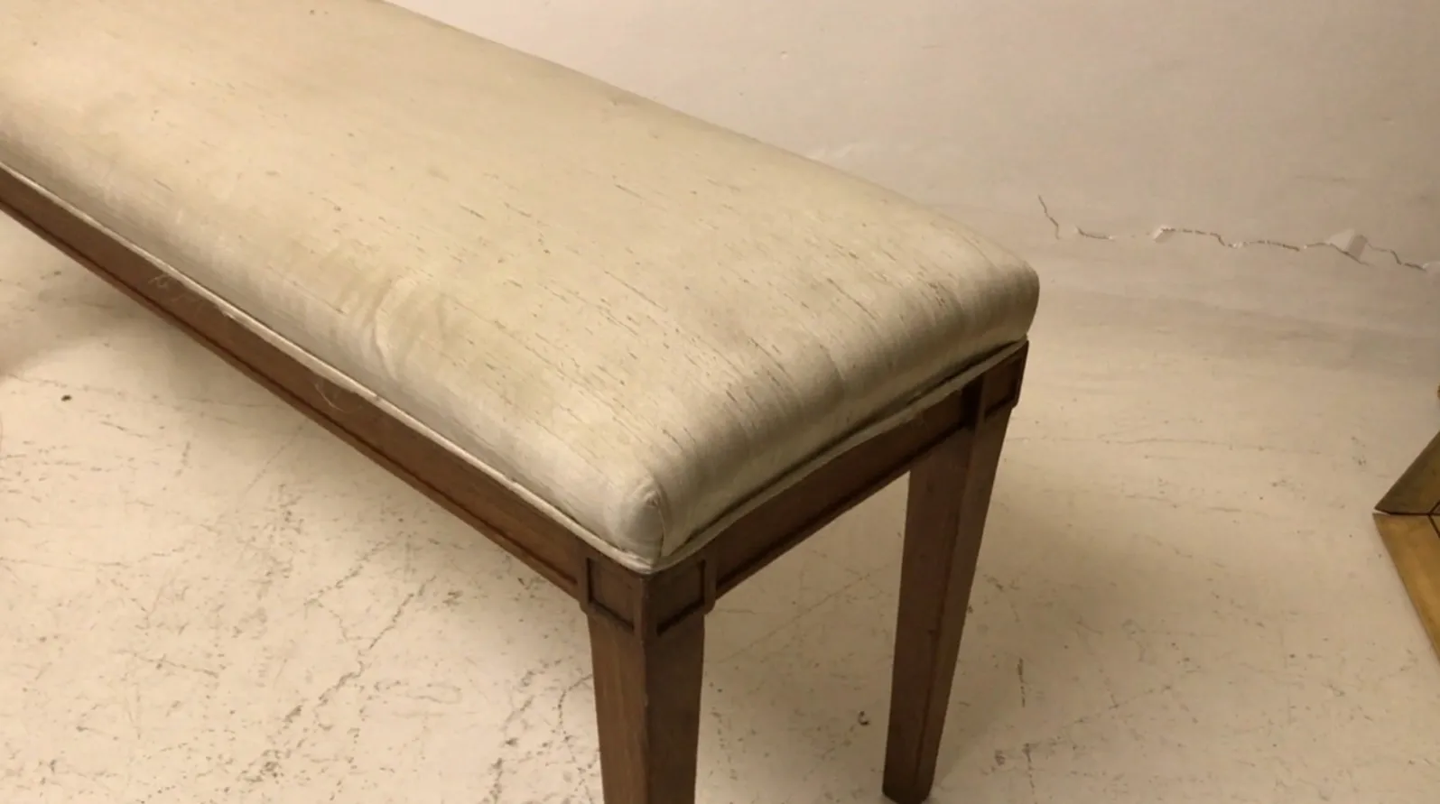 Tabouret antique avec coussin clair, élégant et fonctionnel dans un cadre simple.