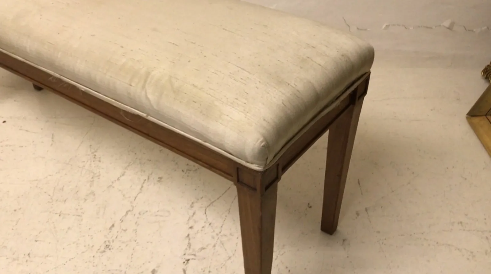 Banqueta antiga com um design acolhedor e confortável, perfeita para qualquer ambiente. Apresenta um assento macio e uma estrutura robusta em tons claros.