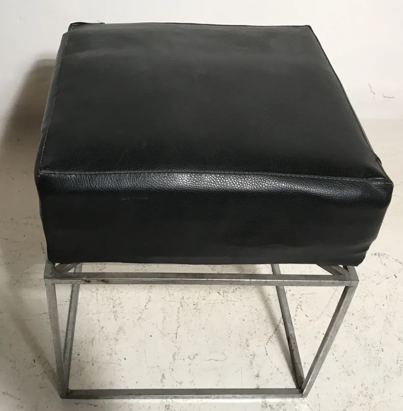 Antiker Hocker in schwarzem Minimalismus mit Metallbasis, einfacher Hintergrund