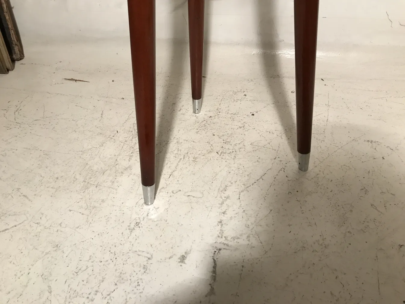 Ancien tabouret avec pattes fines, fond neutre.