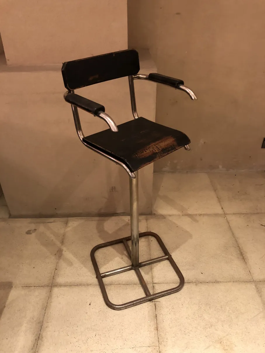 Chaise ancienne avec bras, nécessitant une restauration dans un cadre accueillant.