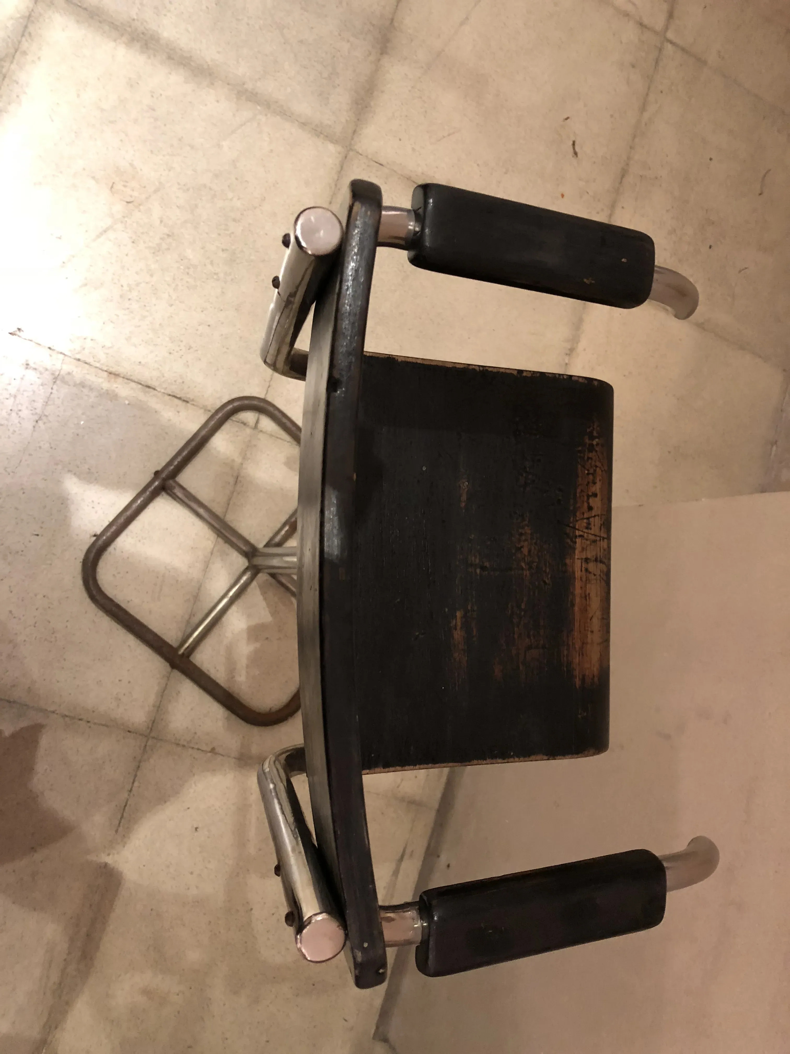 Top view of an antique child chair with arms in a neutral setting.