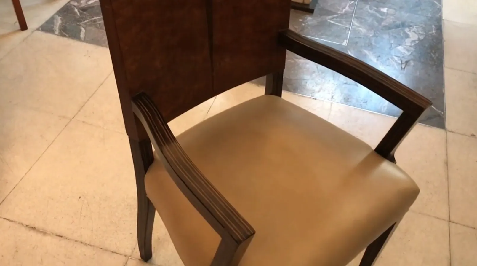 Cadeirão antigo com braços, cor clara em um ambiente elegante