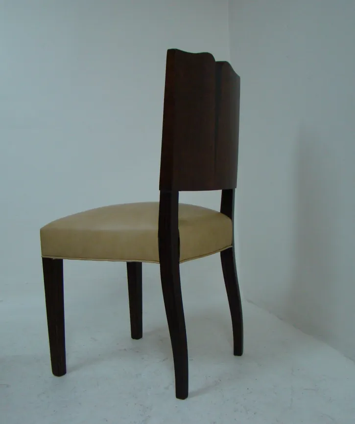 Four antique chairs with an elegant design in a neutral setting.