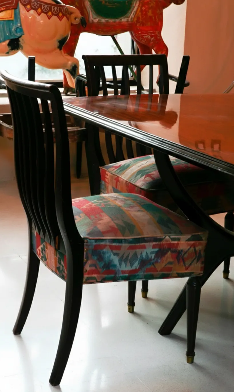 Ocho sillas antiguas de diferentes colores para restaurar, en un ambiente acogedor.