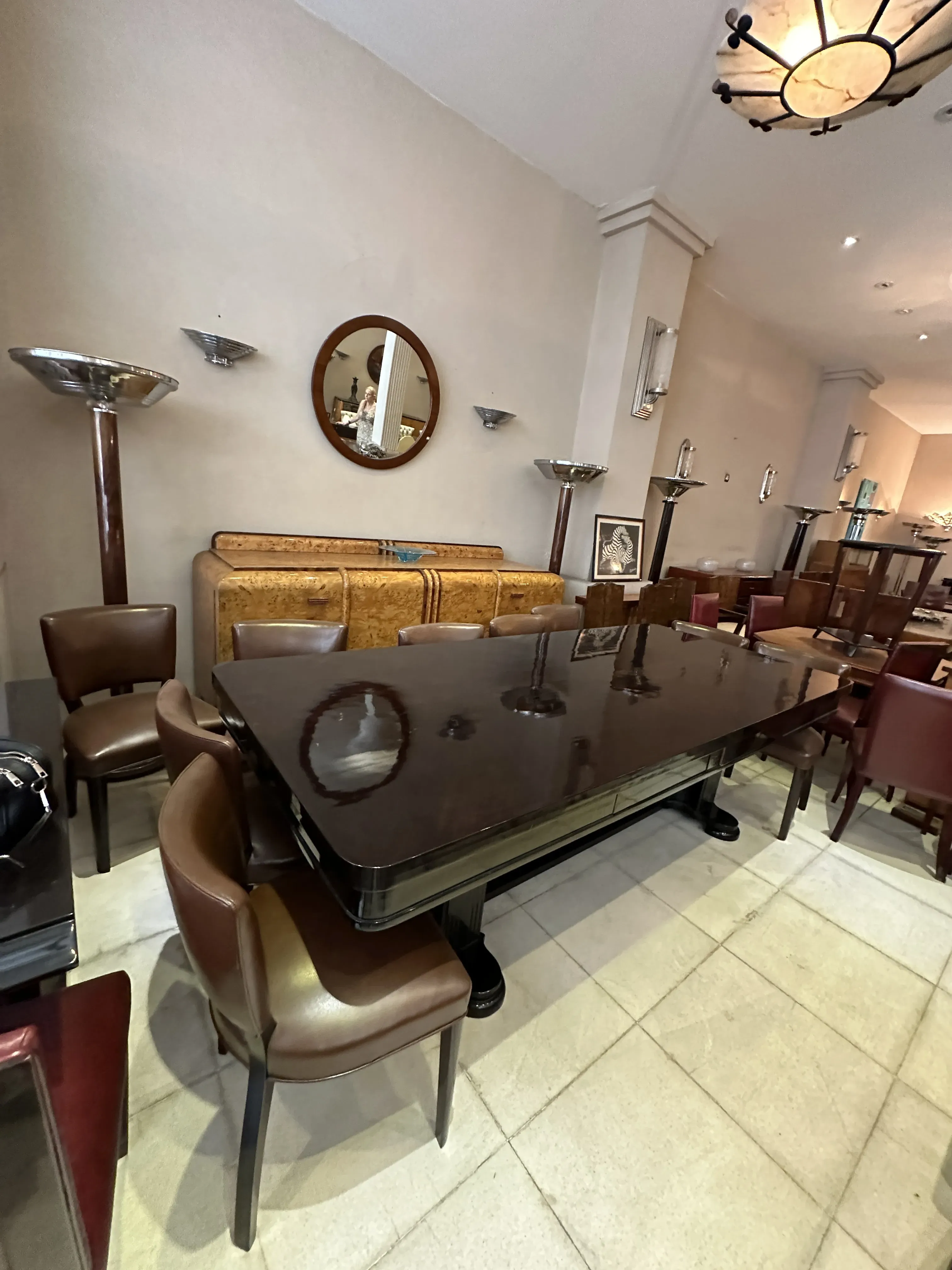 Antique dining table for 10 people with brown leather chairs, cozy atmosphere.