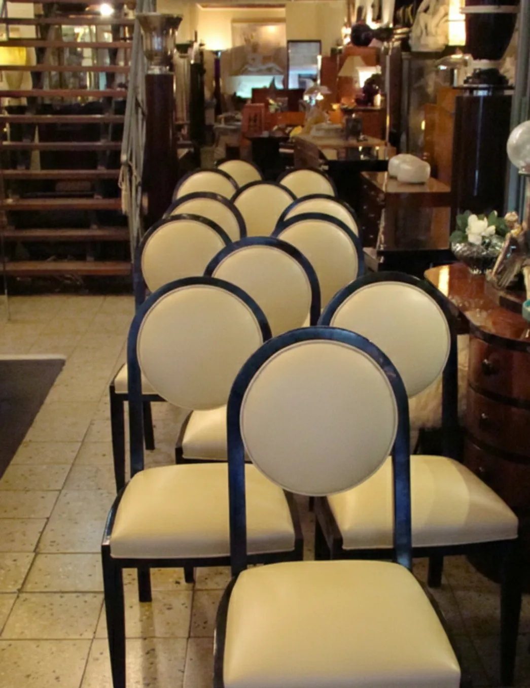 Rows of 12 antique chairs featuring circular backs and light upholstery in a cozy setting.