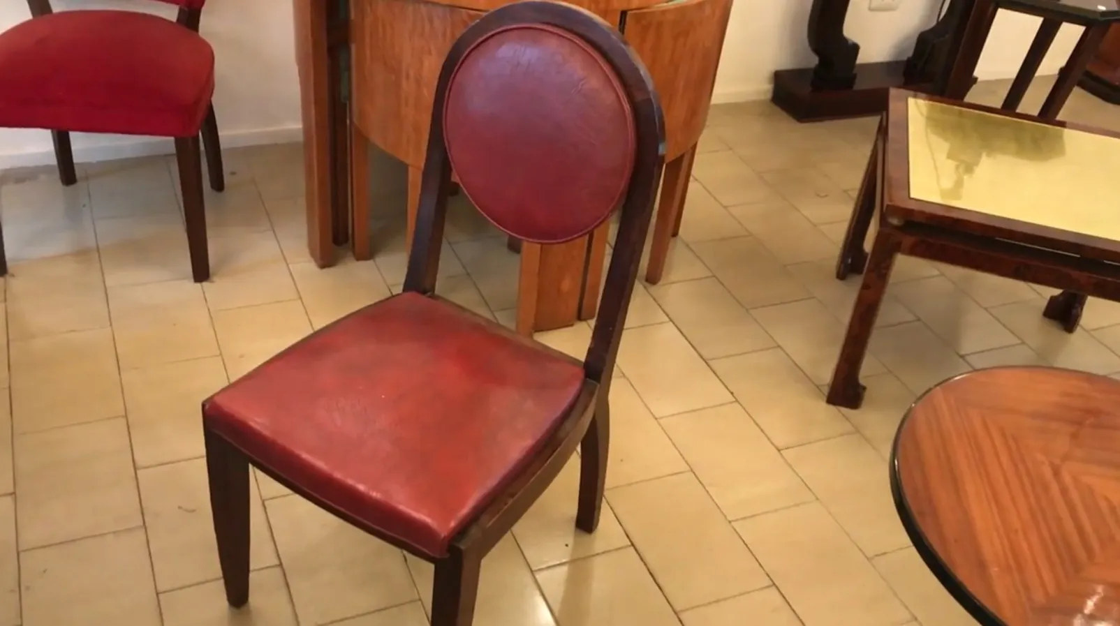 12 cadeiras antigas para restaurar, com assentos vermelhos, em um ambiente aconchegante.