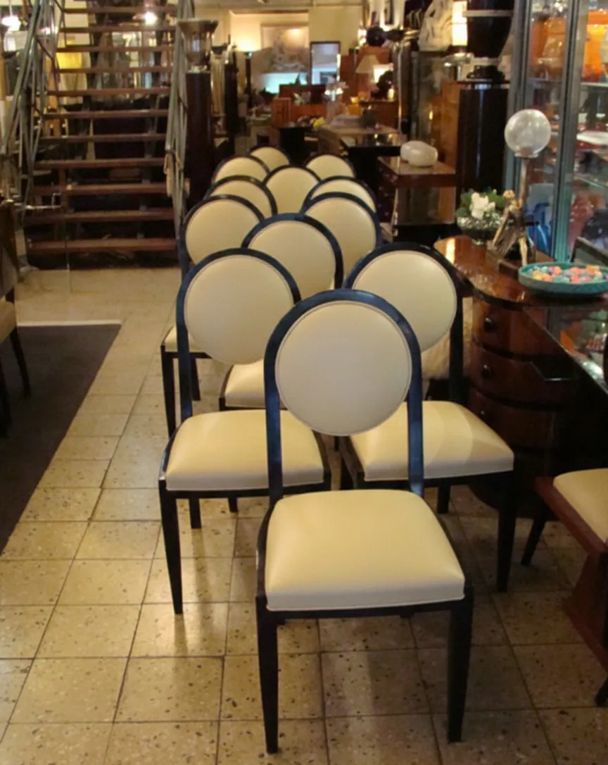 12 sedie antiche con schienale rotondo in stile Art Deco, pronte per essere restaurate, in un ambiente di antiquariato.