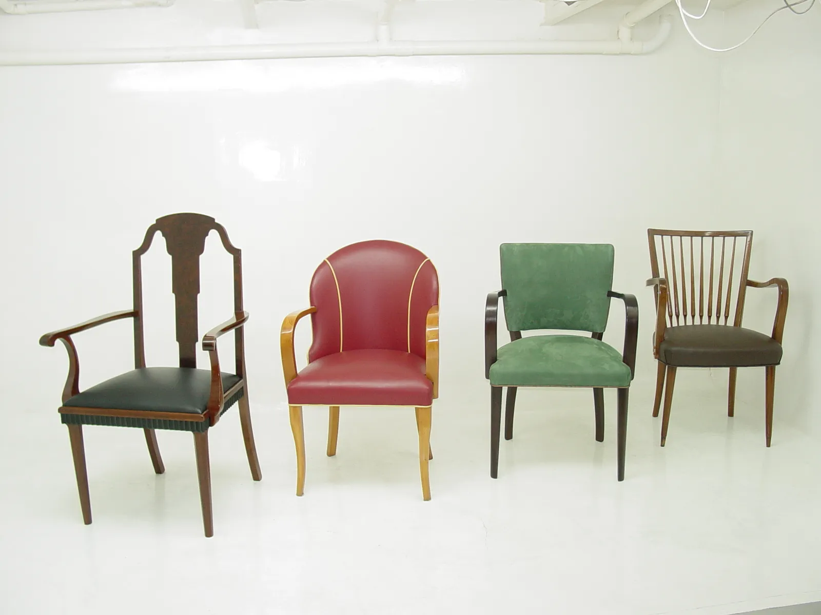 Set di 10 sedie antiche da restaurare, design e colori variati, esposte in un ambiente neutro.