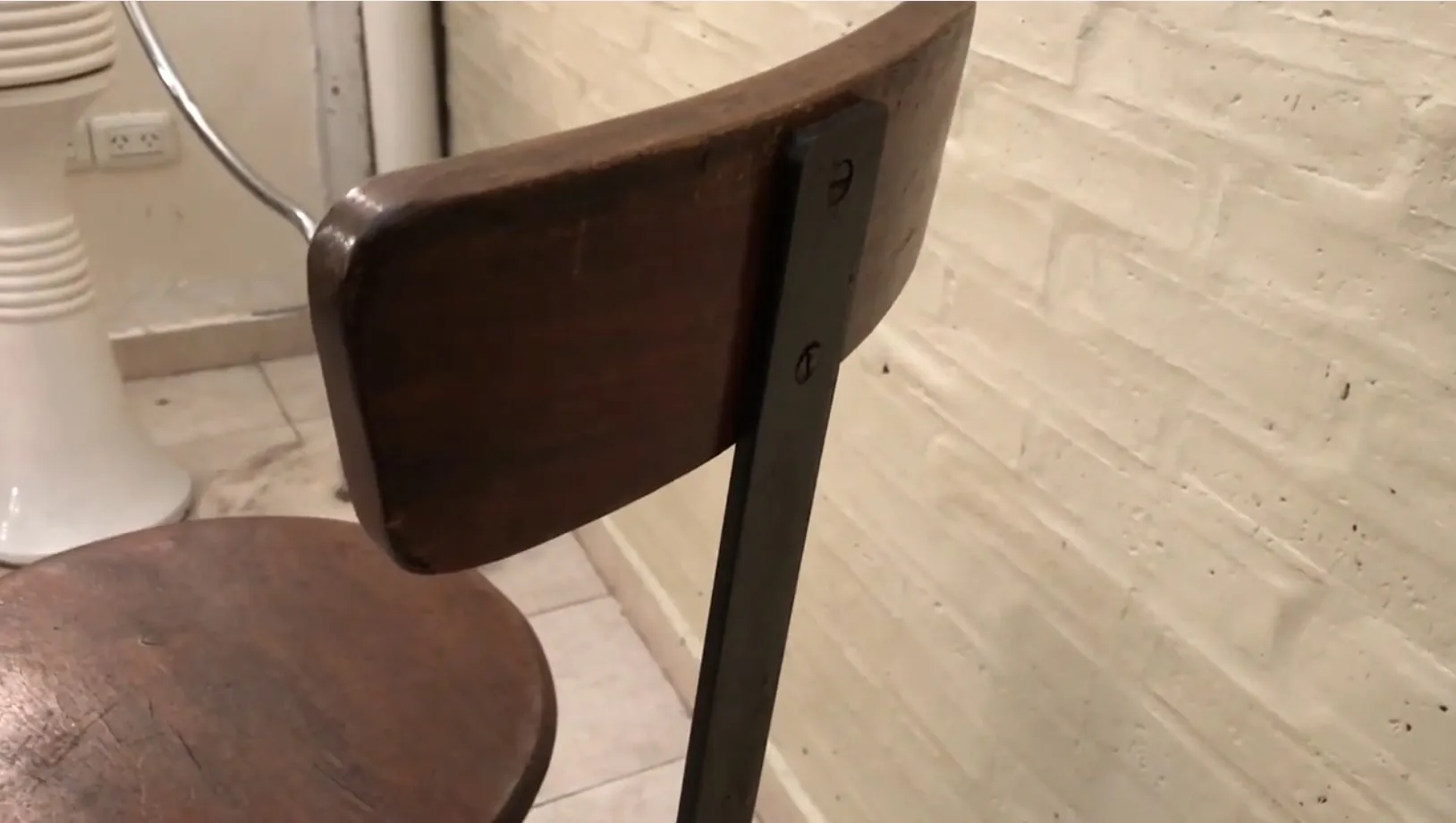 Banqueta antigua con respaldo de madera en un ambiente sencillo.