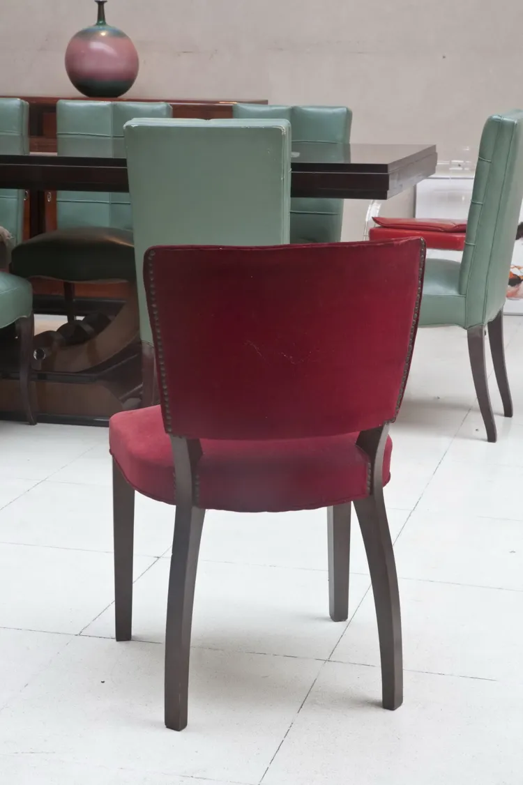 View of 10 antique chairs in a simple setting, some worn