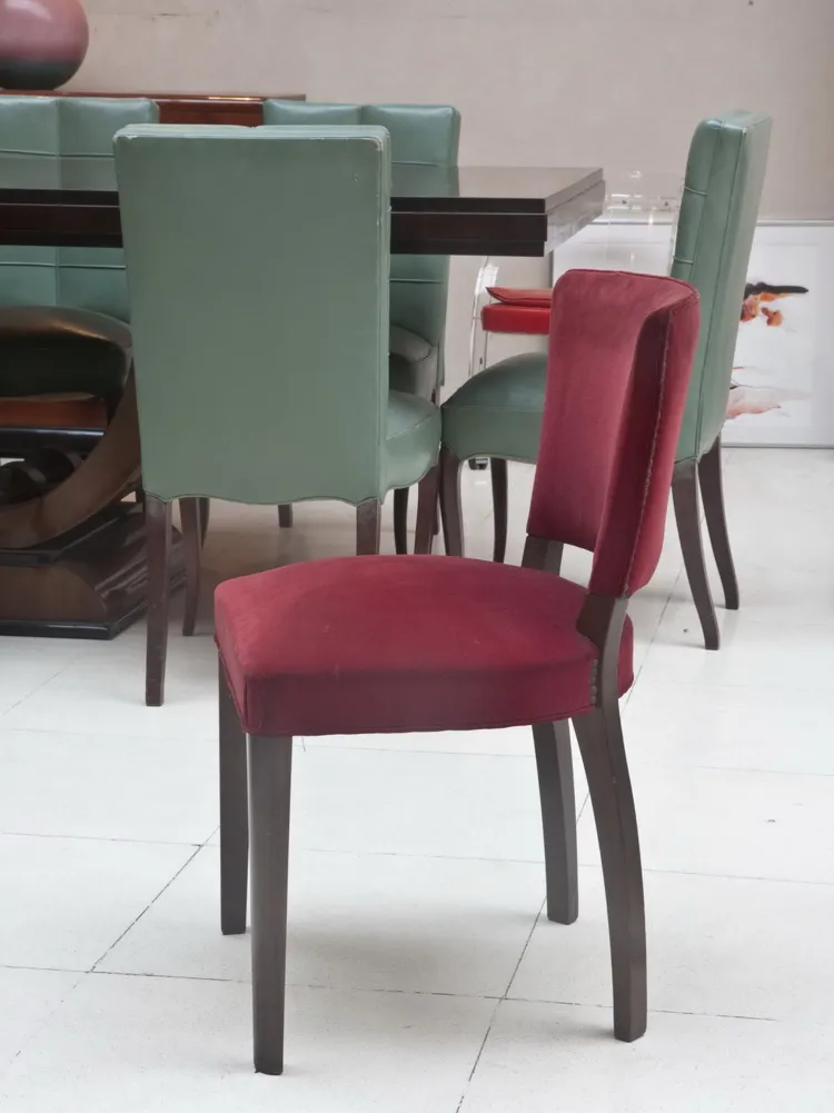 Antique chairs in red and green colors placed in a modern setting.