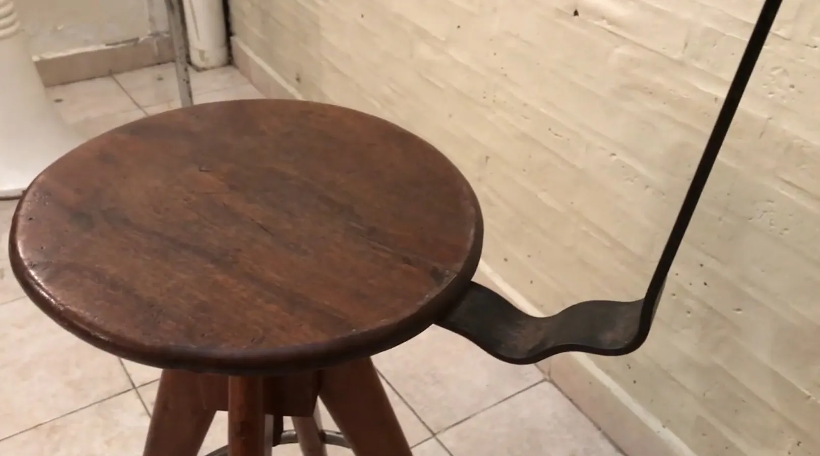 Alter Hocker mit rundem Sitz und Holzbeinen.