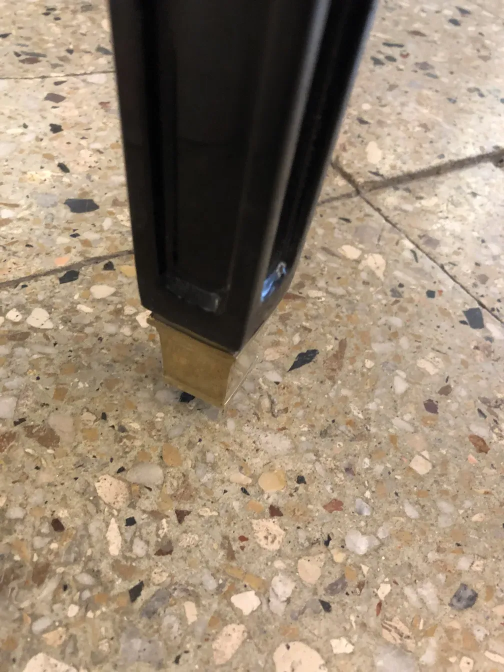 antiker hocker mit metallbasis auf steinboden