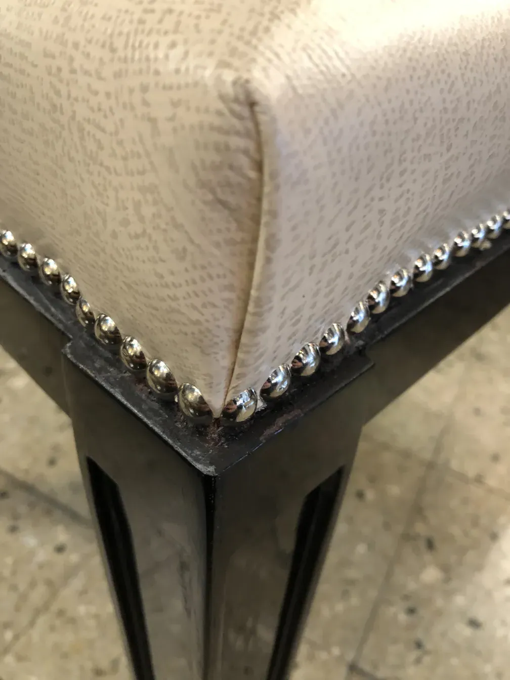 banqueta antigua con cojín decorativo y patas negras