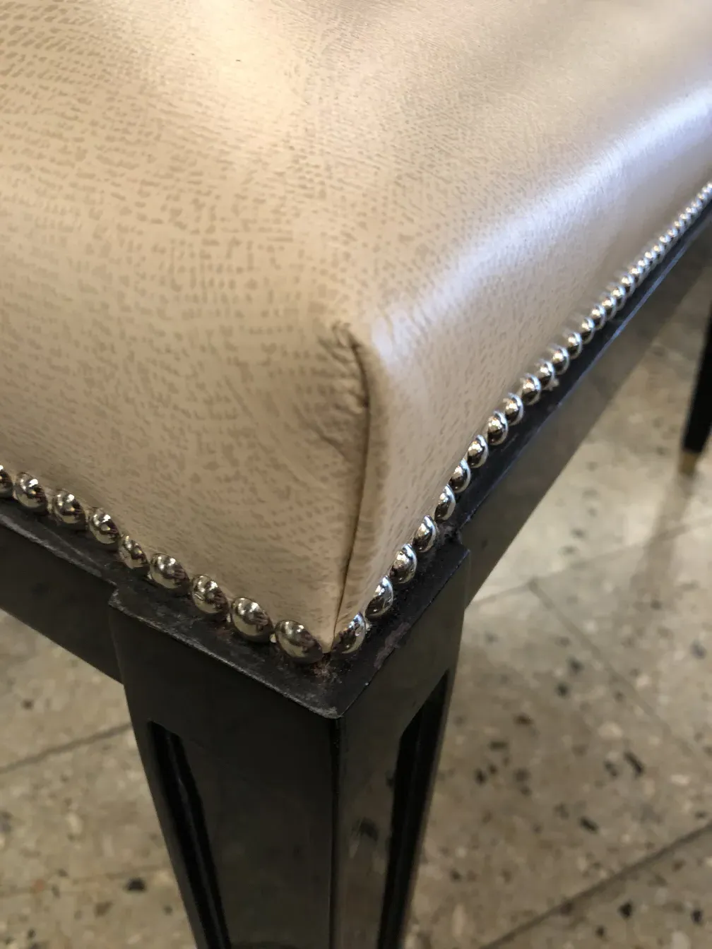 Detail of an antique sidewalk seat featuring decorative upholstery and metallic elements enhancing its design.