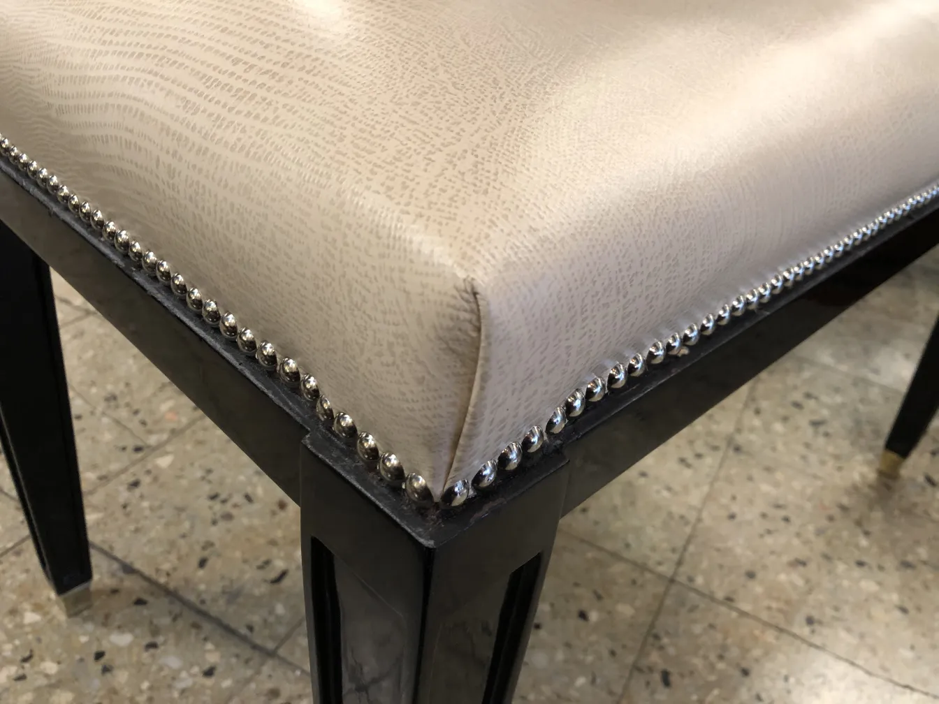 Banqueta antigua con tapizado claro y clavos decorativos