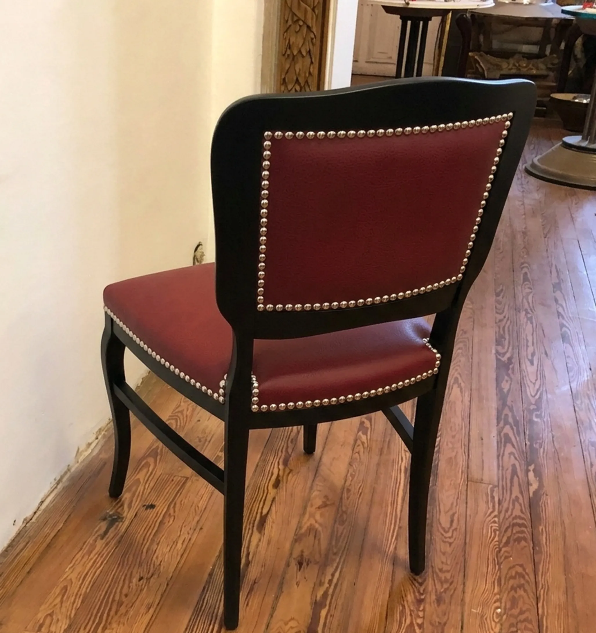Six antique chairs with red upholstery and metal details in a classic setting.