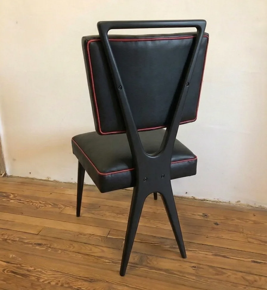 Silla antigua negra con detalles rojos, fondo neutro.