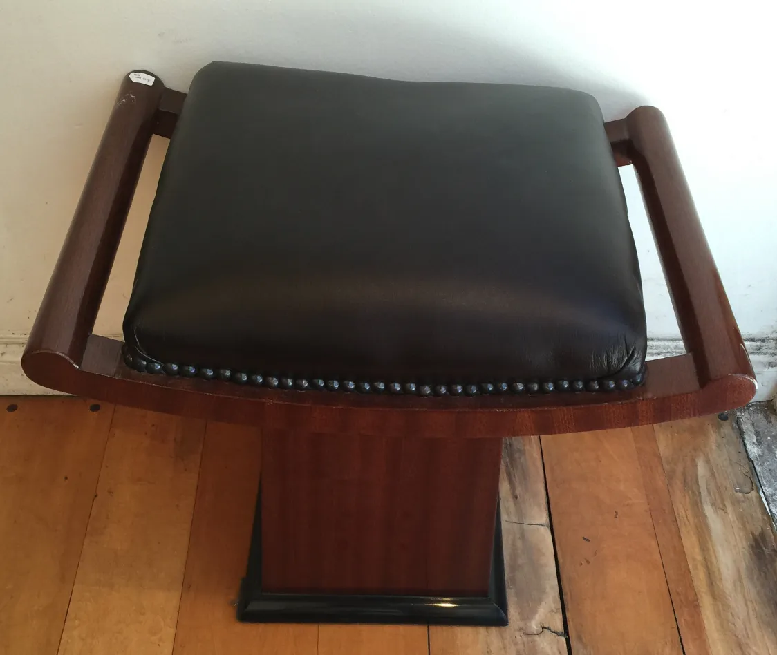 Sgabello antico in legno con seduta nera e braccioli, dettaglio elegante.