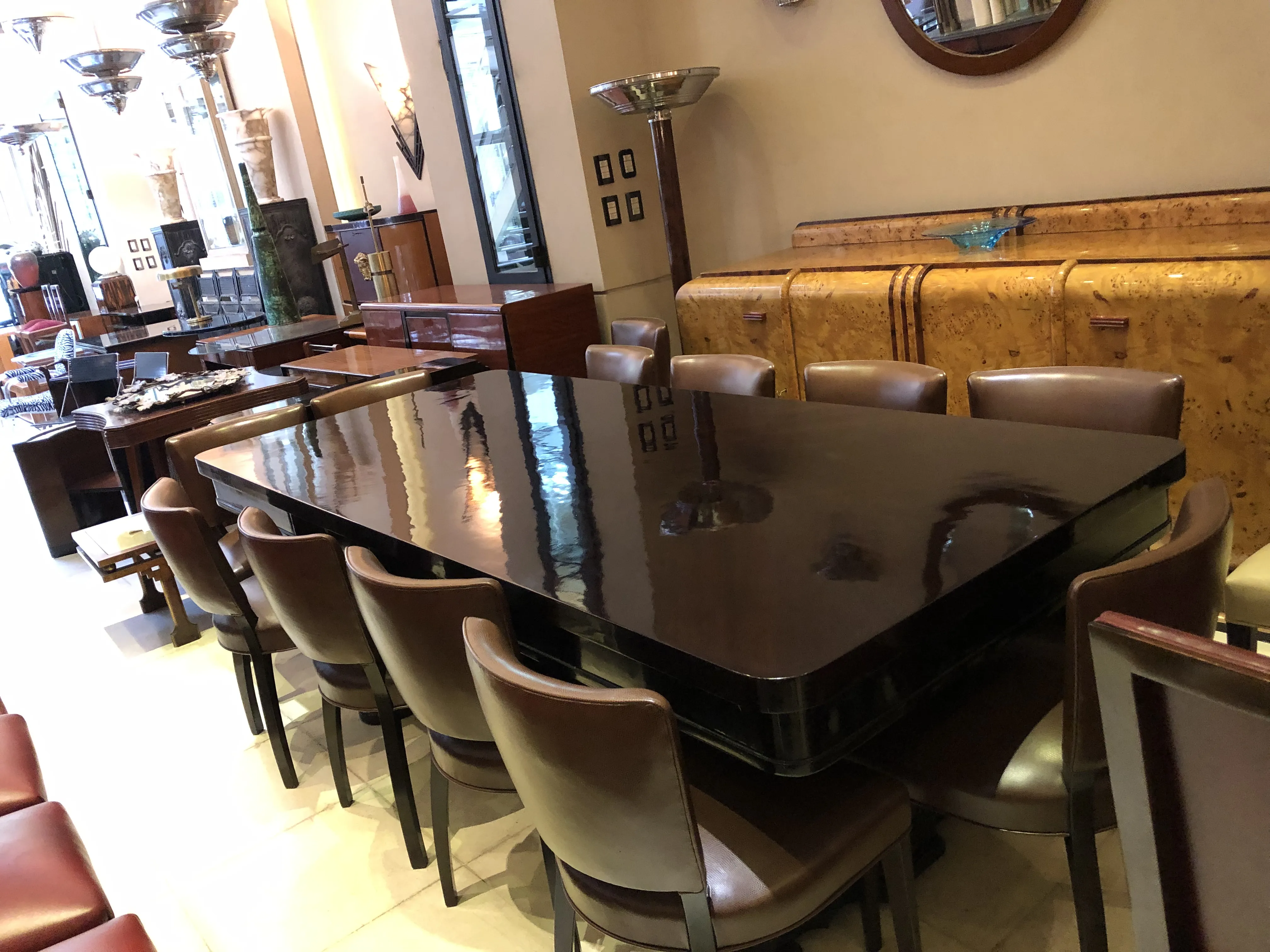 Antique dining table in Art Deco style for 10 people, surrounded by chairs.