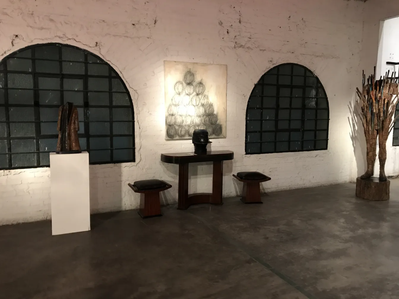 Due sgabelli in una galleria d'arte con opere e sculture.