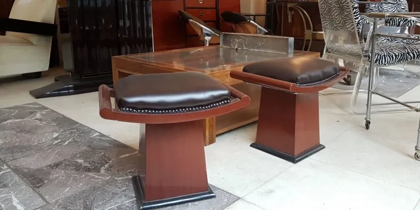 Conjunto de banquetas em um ambiente aconchegante, com estofado escuro e base elegante. Perfeito para decorações antigas.