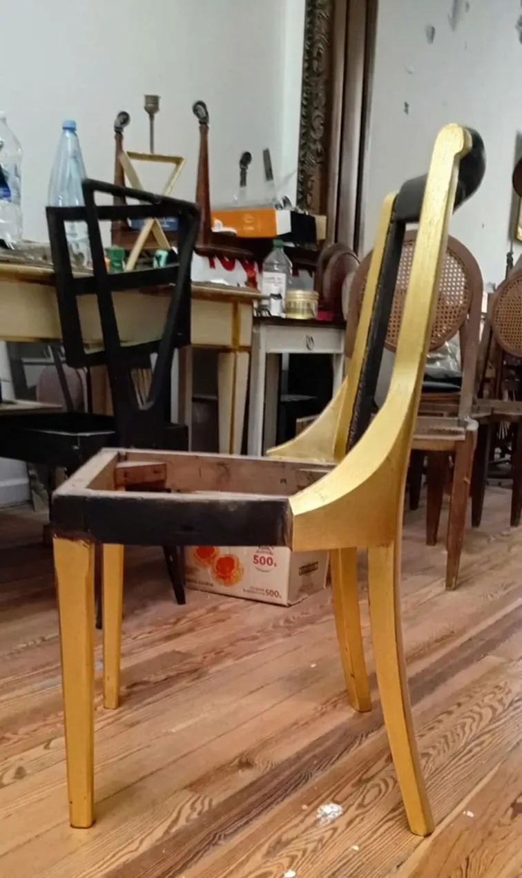 6 cadeiras em processo de restauração, algumas pintadas e outras aguardando reparo, ambiente com antiguidades.