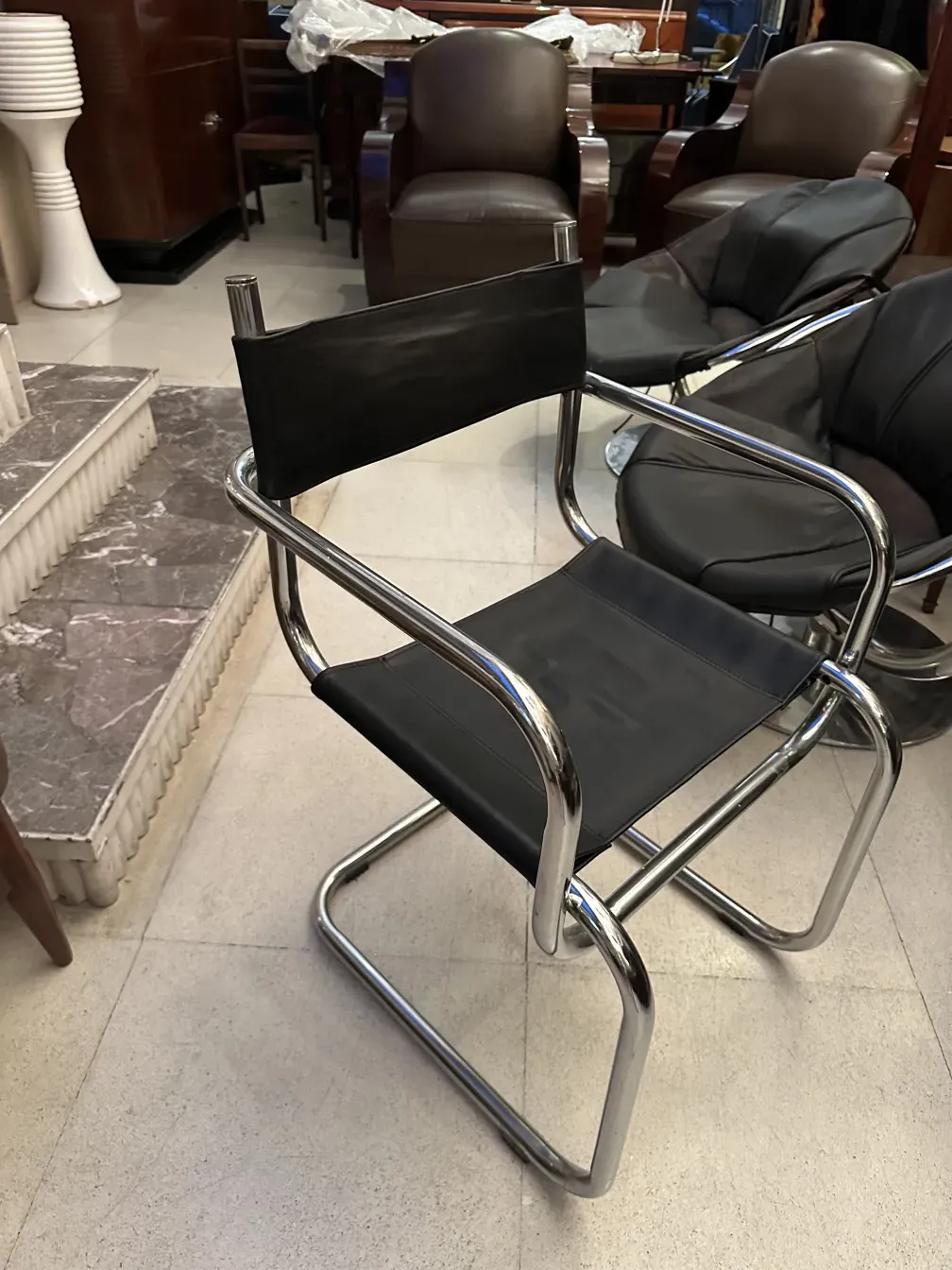 vier antike Stühle mit schwarzer Oberfläche und Metallelementen in einem eleganten Umfeld