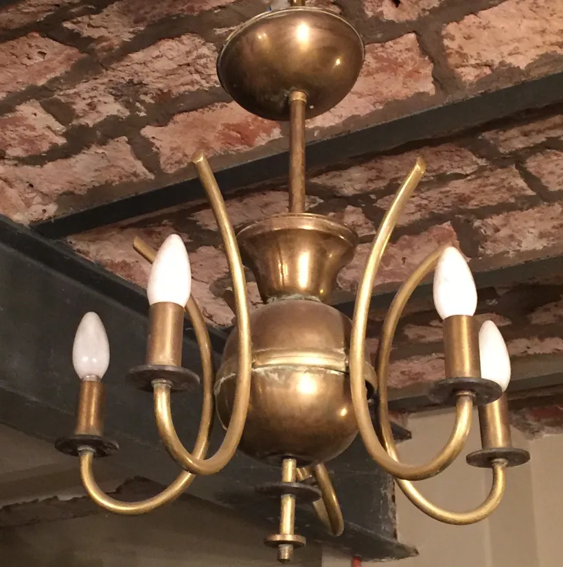 lustre antique Art Deco avec bras courbes et ampoules blanches dans un cadre confortable